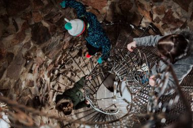 Two people descend a spiral staircase in a castle in Colorado.