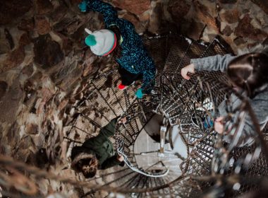 Two people descend a spiral staircase in a castle in Colorado.