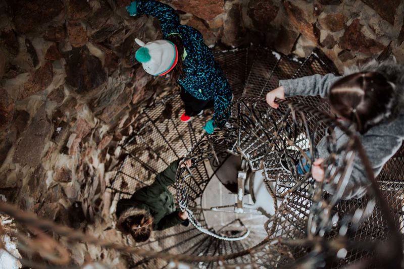 Two people descend a spiral staircase in a castle in Colorado.