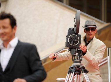 Camera operator filming an actor on set.