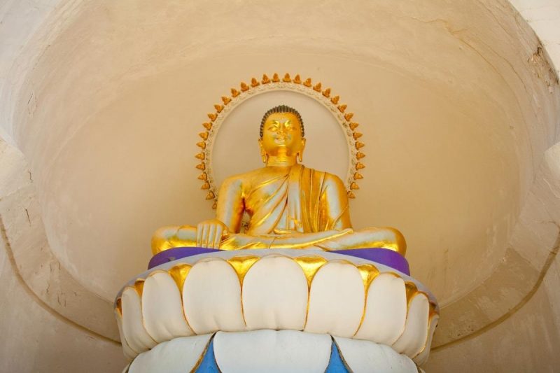 Close up of a golden Buddha statue on a pedestal at the Peace Pagoda in Massachusetts.