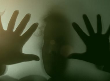 A blurry figure through a dark see through glass window.