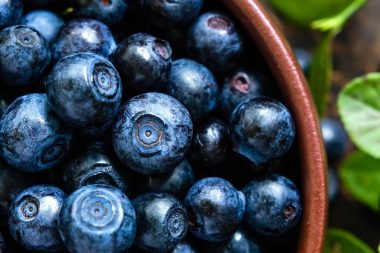 Close up of a wooden bowl of freshly washed blueberries.