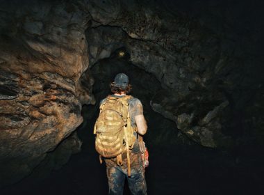 Exploring a dark, abandoned tunnel with flashlights at night.