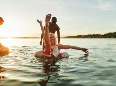 Friends with inner tubes enjoying an evening swim in a state park recreational lake.