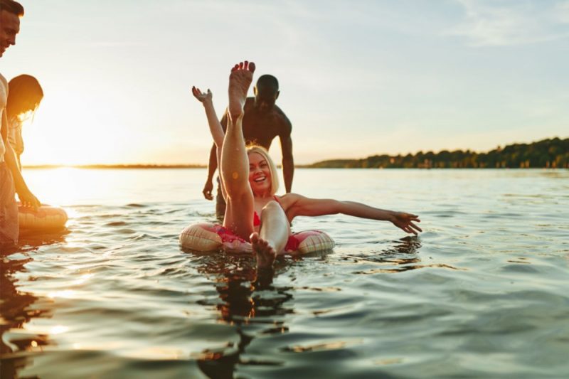Friends with inner tubes enjoying an evening swim in a state park recreational lake.