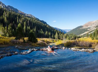 A man soaks in a hot spring in the mountains.