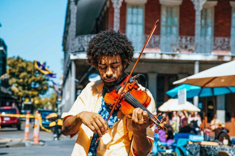 A musician plays his violin on the street in New Orleans, The Big Easy, on a beautiful sunny day.